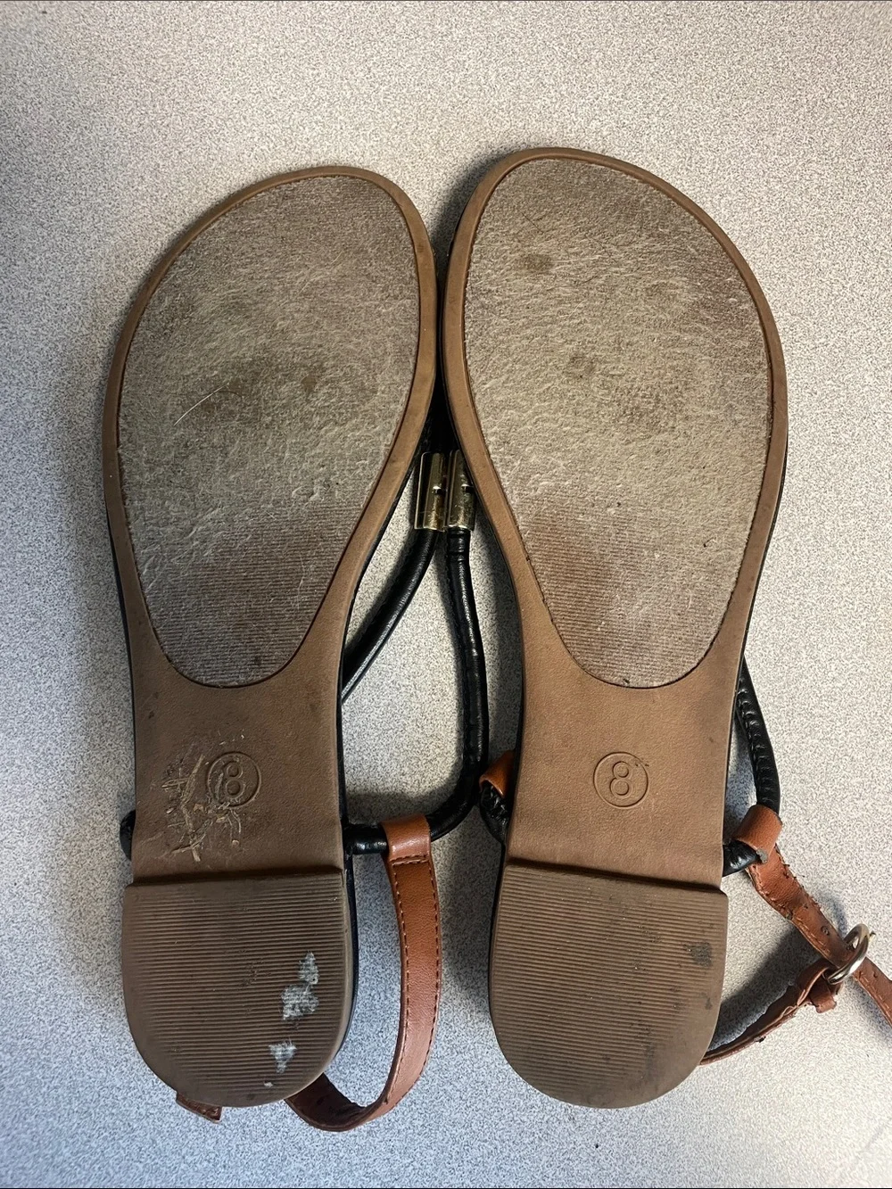 Black and brown t-strap sandals with gold accents